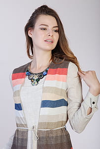 woman wearing multicolored striped long-sleeved dress holding hair behind white wall thumbnail