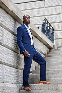 man in blue 2-piece suit standing on staircase thumbnail
