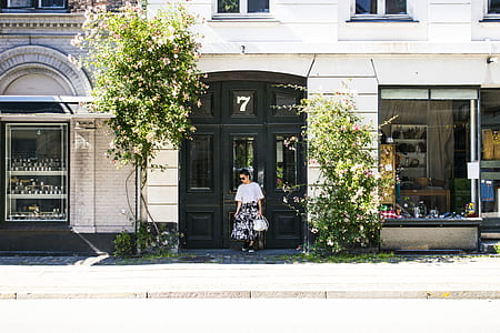 woman stands near trees beside building thumbnail