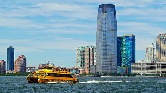 A yellow New York Water Taxi cruises pass Jersry City waterfront on the Hudson River out toward New York Harbor for a siteseeing cruise. thumbnail