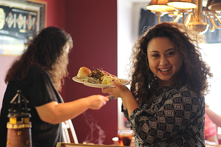 smiling woman in black and grey top holding ceramic plate during daytime thumbnail