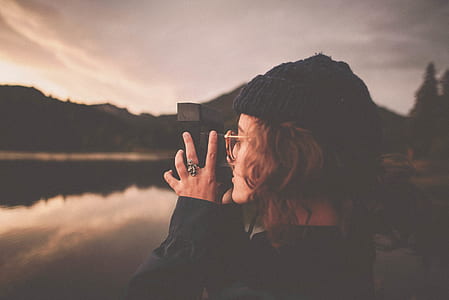 woman using camera in front of body of water thumbnail