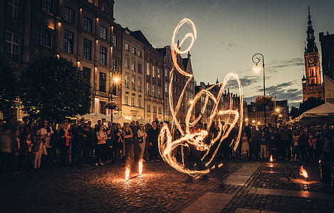 time lapse photo of person fire dancing near crowd of people during golden hour thumbnail