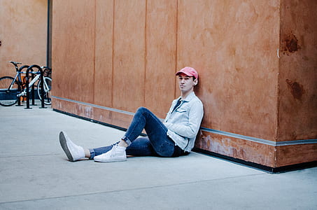man sitting on floor leaning on brown wall thumbnail
