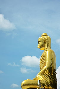 gold-colored sitting Buddha statue under white clouded blue sky at daytime thumbnail
