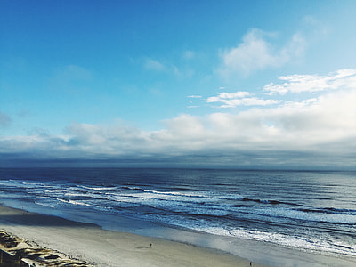 people walking on beach under cloudy blue sky during daytime thumbnail
