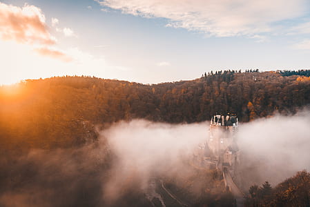 white and black castle surround with fogs and trees under blue sky during daytime thumbnail