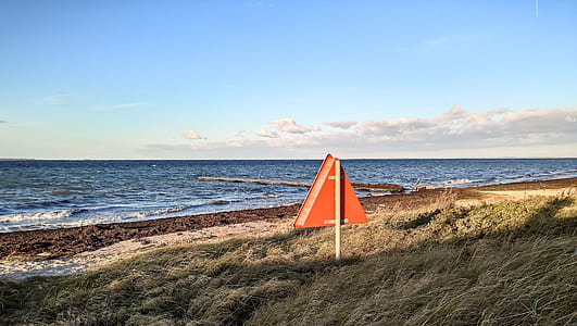 orange triangle signage near sea thumbnail