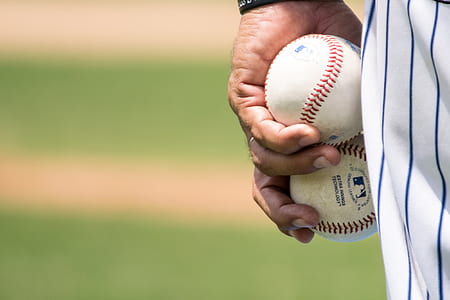 man holding two baseballs standing in baseball stadium thumbnail