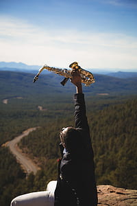 shallow focus photography of man holding saxophone thumbnail