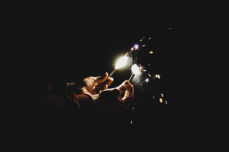 low-light photography of person holding sparklers thumbnail