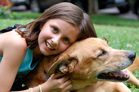 girl wearing green sleeveless shirt lying on short-coated brown dog thumbnail