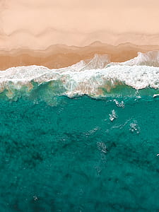 aerial view of flowing sea water beside seashore thumbnail
