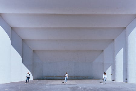 three women standing near white wall thumbnail