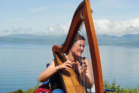 woman playing harp near bodies of water during daytime thumbnail