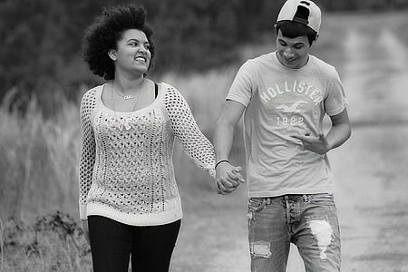 grayscale photography of man and woman holding hands while walking thumbnail
