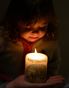 girl facing at lit pillar candle thumbnail