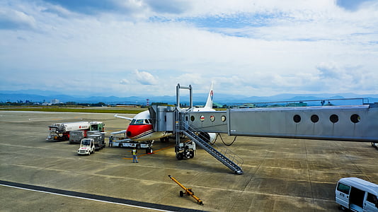 white and red airliner unloading passengers under blue sky at daytime thumbnail