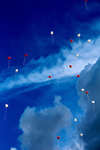 white and red balloons flying through the sky thumbnail