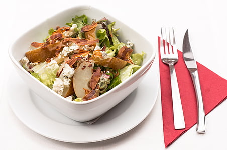 vegetable salad in white bowl on white plate with fork and knife thumbnail