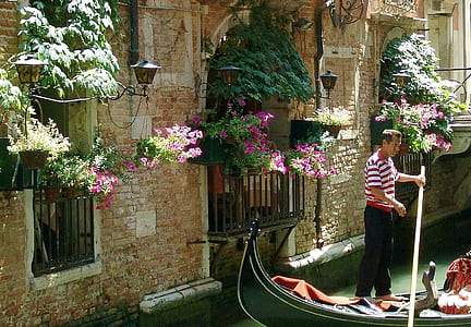 man riding boat holding brown stick near gray wall thumbnail