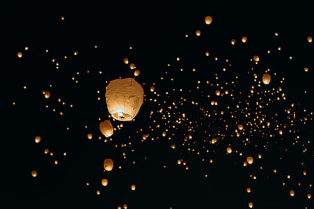 beige sky lanterns floating in the dark night sky thumbnail