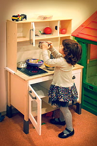 girl in gray and blue floral long-sleeved dress playing kitchen play set thumbnail