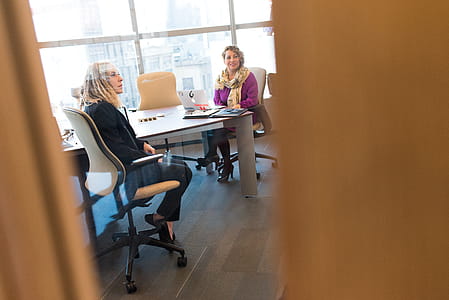 Two Women Sitting Near White Table thumbnail