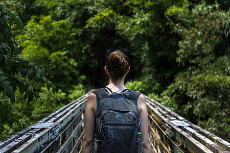 woman carrying backpack walking on bridge thumbnail