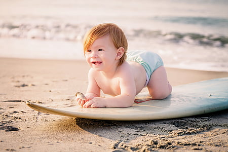 girl riding on brown surfboard near seashore at daytime thumbnail