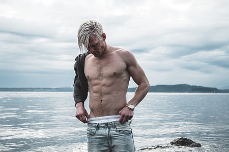standing man wearing denim jeans near water thumbnail