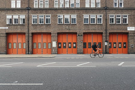 man riding bike near brown building at daytime thumbnail