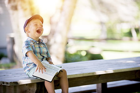 boy reading bible sitting on chair during daytime thumbnail