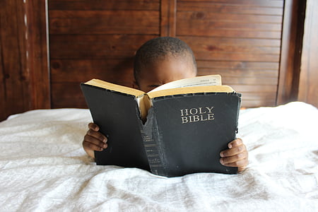 boy lying on bed reading Holy Bible thumbnail