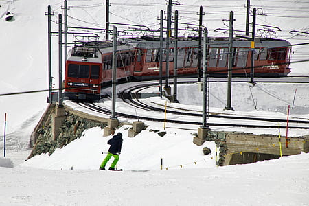 photo of man skiing near train on snowy field during daytime thumbnail