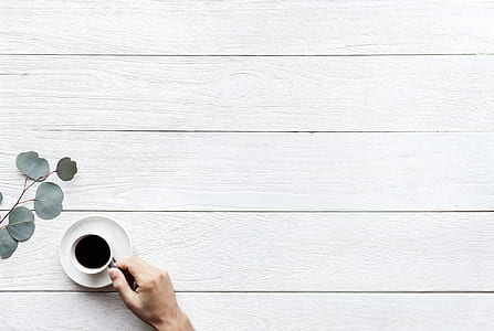 person hand holding a cup of coffee on white table thumbnail