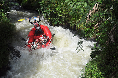 group of men playing inflatable kayak on cascade waterfalls between trees thumbnail