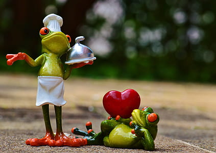 bokeh shot of two green chef frogs figurines thumbnail