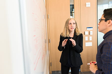 Woman Wearing Suit Jacket Standing In Front Of Whiteboard thumbnail
