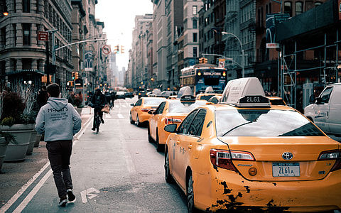man standing near yellow Toyota taxi near buildings at daytime thumbnail