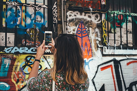 woman taking a picture of wall art during daytime thumbnail