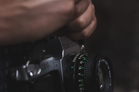 person holding gray Canon SLR camera thumbnail