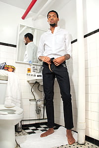 barefoot man wearing black pants and white dress shirt standing on towel inside bathroom thumbnail