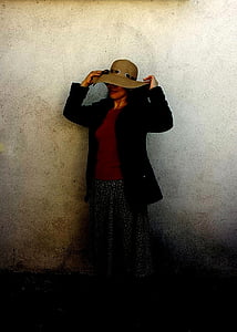 woman standing while putting hat on thumbnail