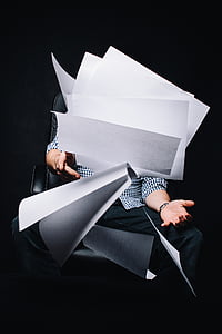 man sitting on rolling chair covering face by white printer paper thumbnail