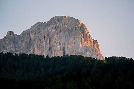 green forest near brown mountain under clear sky thumbnail