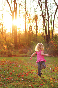 girl wearing pink tank top and gray denim pants running on green grass field during daytime thumbnail