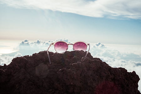 white framed sunglasses on rock overlooking clouds thumbnail