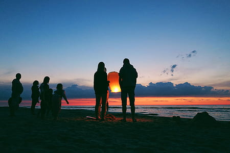 silhouette of people on seashore at golden hour thumbnail