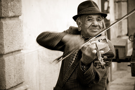 sepia photography of man playing violin outdoors thumbnail